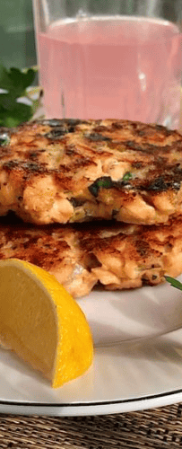 Two salmon cakes made with fresh salmon with lemon wedges