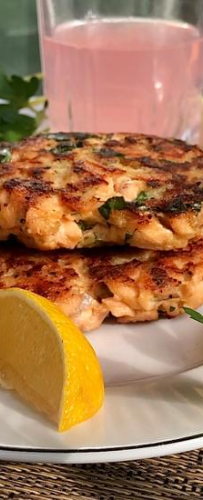 Two salmon cakes made with fresh salmon with lemon wedges